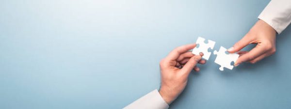 The man and woman holds in hand a jigsaw puzzle. Business solutions, success and strategy concept.